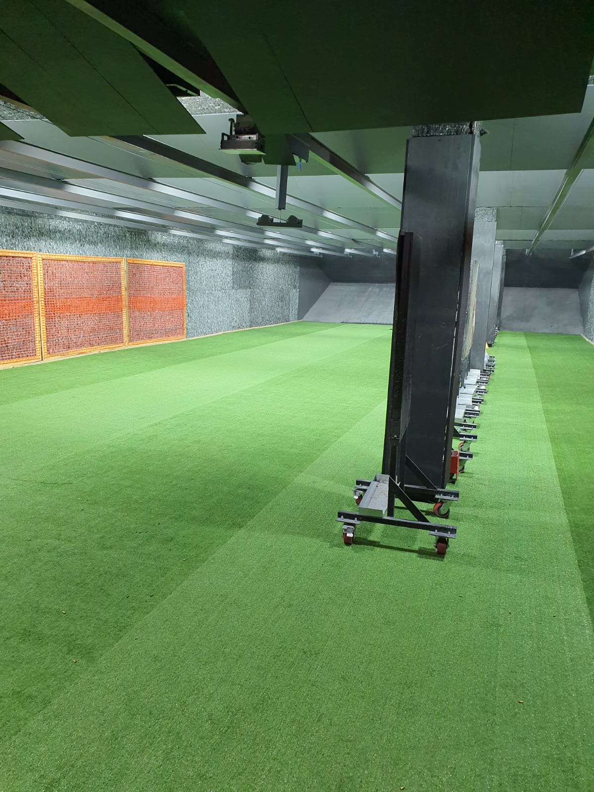 Indoor range bay with movable target stands on castors parked along the wall