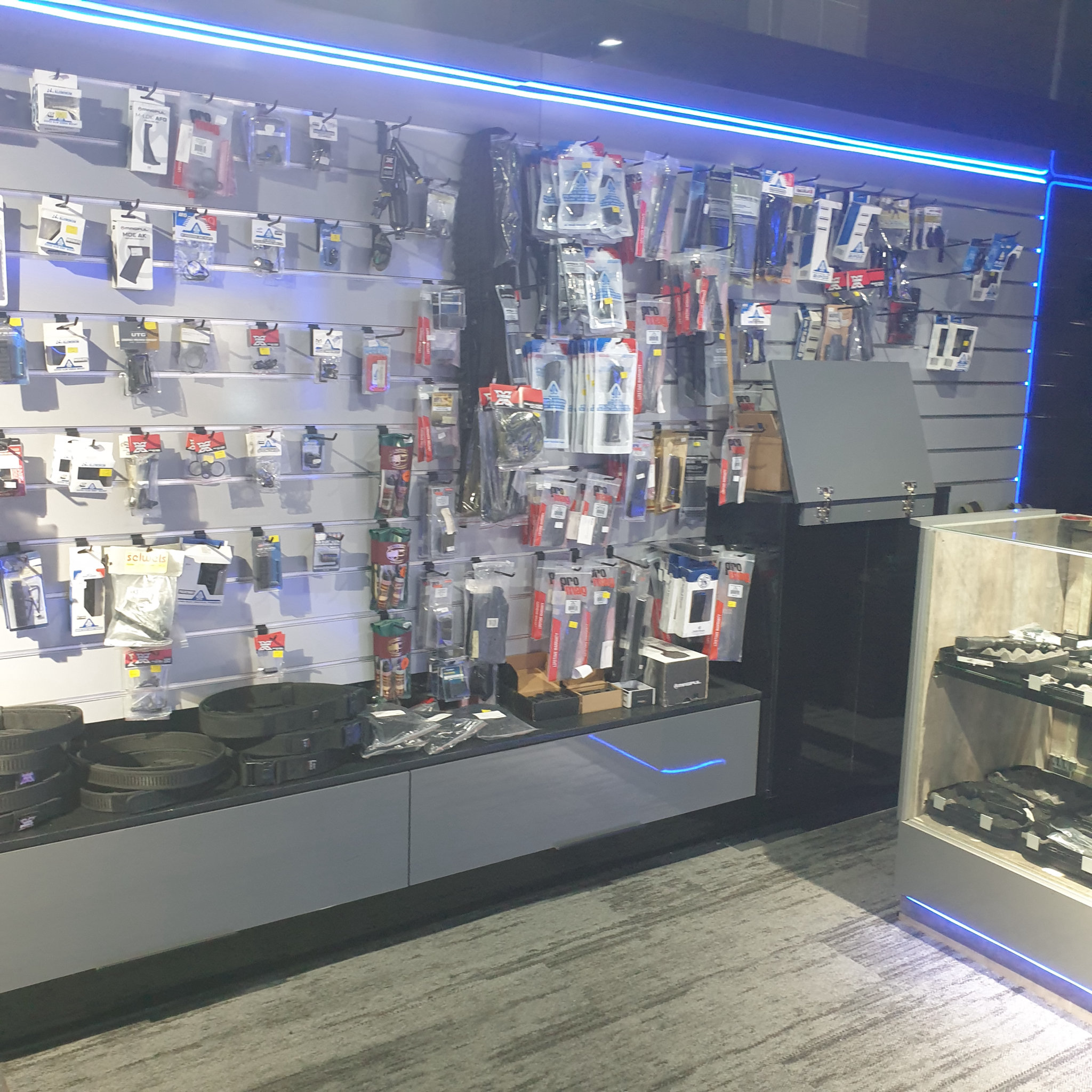 Angled view along the accessories wall towards the glass counter and its pistol cases