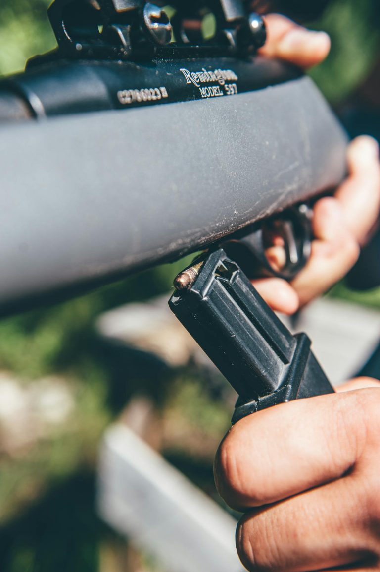 Detailed view of hands reloading a rifle with selective focus outdoors.